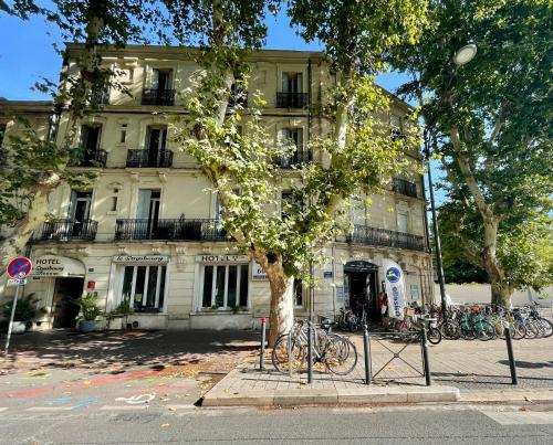 a tree in front of a building with bikes parked in front at Le Strasbourg Hotel in Montpellier
