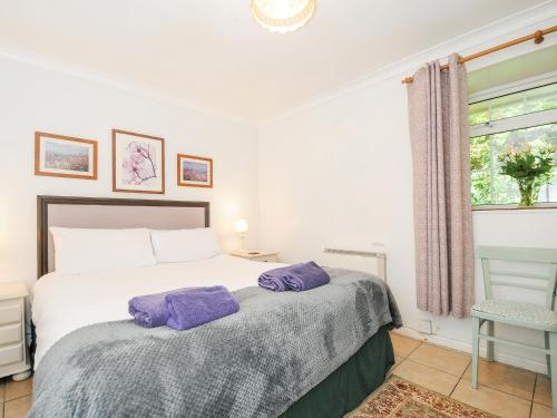 a bedroom with a bed with purple towels on it at Forge Cottage in Helston