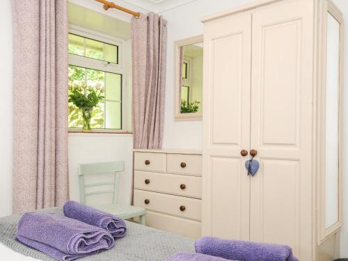a bedroom with a bed and a dresser and a window at Forge Cottage in Helston