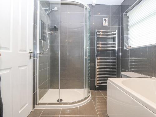 a bathroom with a shower with a glass door at Cynefin in Llangefni