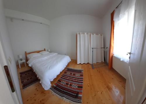 a bedroom with a white bed and a rug at Dona 2 in Sarajevo