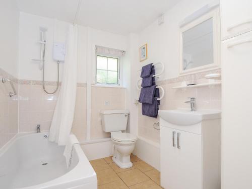 a white bathroom with a toilet and a sink at Dairy Cottage in Helston