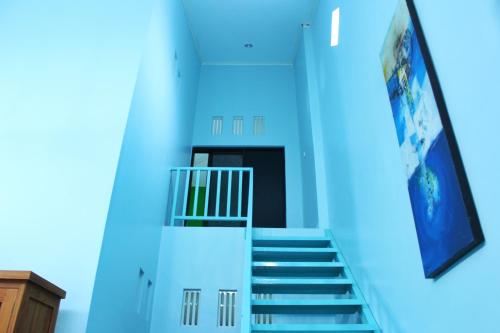 klatka schodowa w budynku z niebieskimi ścianami i ekranem w obiekcie KJ Blue House Senggigi w mieście Senggigi