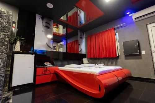 a red bed in a room with a mirror at Troia Motel in Foz do Iguaçu