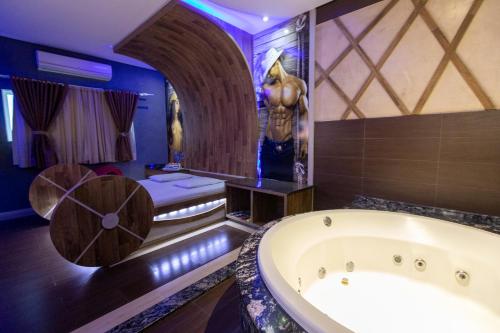 uma casa de banho com banheira e uma cama num quarto em Troia Motel em Foz do Iguaçu