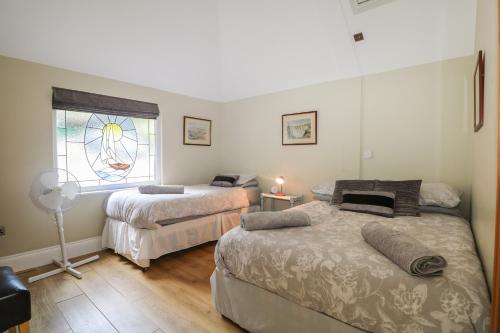 a bedroom with two beds and a window at Garden Cottage in Farnham