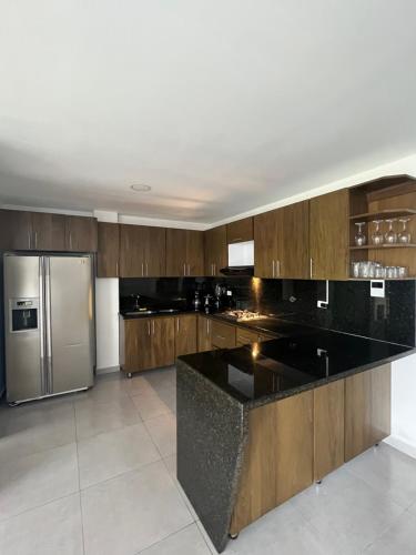 a kitchen with wooden cabinets and a stainless steel refrigerator at Casa campestre en el corazón de envigado in Envigado