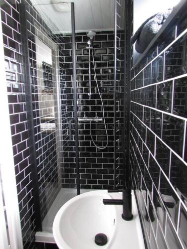 La salle de bains est pourvue de carrelage noir, d'une douche et d'un lavabo. dans l'établissement Les pieds dans l' eau, à Bretignolles-sur-Mer