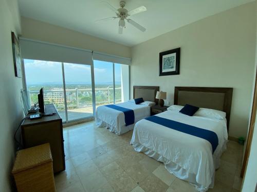 a hotel room with two beds and a balcony at Departamento Playa Punta Diamante in Acapulco