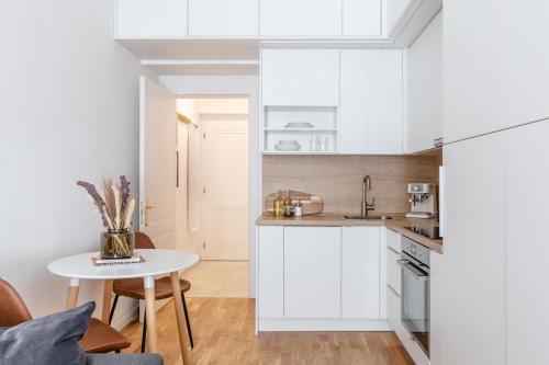 a kitchen with white cabinets and a small table at TurnKey I Cozy Studio by Letna Park in Prague