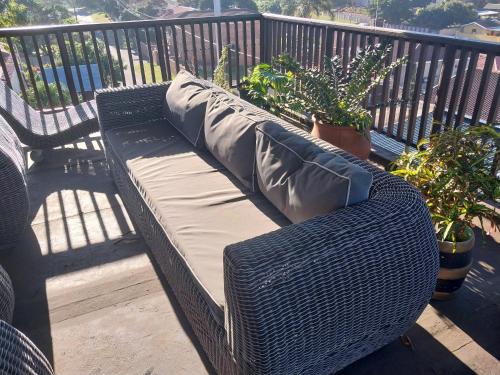 a wicker bench sitting on a balcony with plants at Busis guesthouse in Durban
