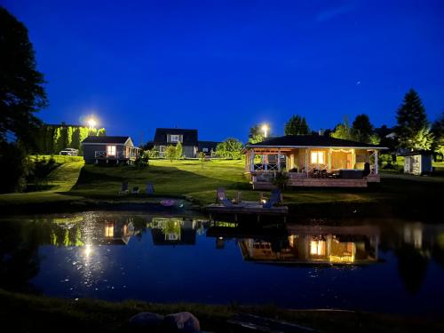 a house with a gazebo next to a lake at night at Gandro lizdas in Lekėčiai