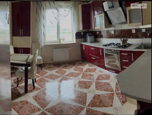 a kitchen with red cabinets and a table and a stove at Bulvar in Ivano-Frankivsʼk