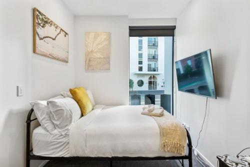 a white bedroom with a bed and a tv at Cosy Studio in Central Avondale - Netflix Wi-Fi in Auckland