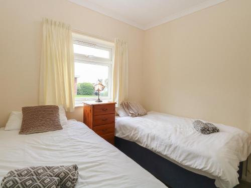 two beds in a room with a window at 31 Siesta Mar Chalet Park in Norwich