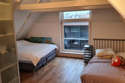 a bedroom with two beds and a window at Groot mooi 2 etage loft met dakterras in De Pijp. in Amsterdam