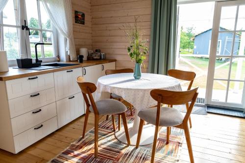 a kitchen with a table with chairs and a vase of flowers at Gandro lizdas in Lekėčiai