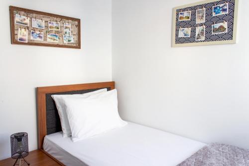 a bedroom with a white bed with two pictures on the wall at Long Beach Rental Apartments in Trikomo