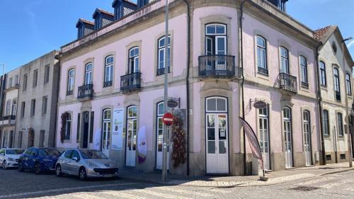 a pink building with cars parked in front of it at Coreto Bento Freitas in Vila do Conde