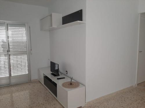Cette chambre blanche dispose d'une télévision murale blanche. dans l'établissement Apartamento Juan, à Vejer de la Frontera