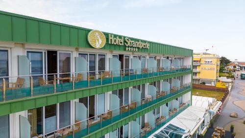 a hotel with a green and white building at Hotel Strandperle in Cuxhaven