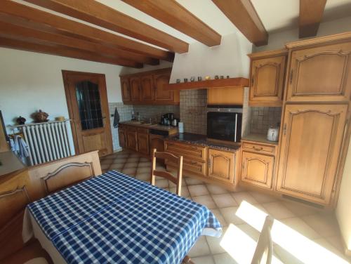 une cuisine avec des placards en bois et une table avec un chiffon de table bleu dans l'établissement Appartement des rives de l'Ehn, à Krautergersheim