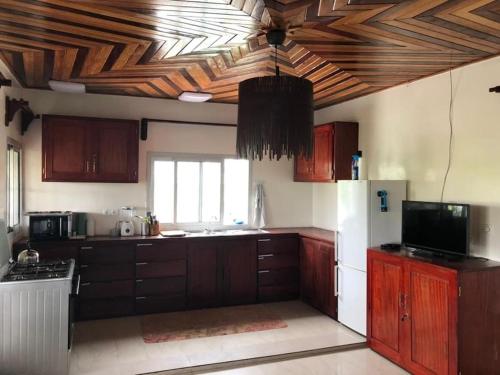 - une cuisine avec des placards en bois et un réfrigérateur blanc dans l'établissement Deux-Palmes-Kribi, proche de la plage, confortable et adapté aux familles, à Kribi