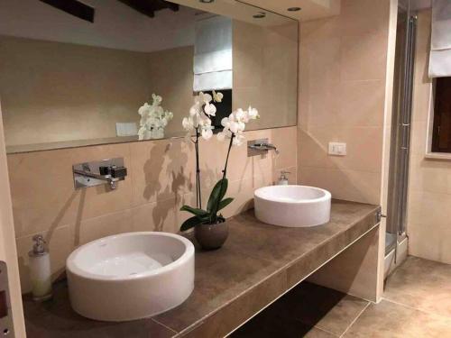 a bathroom with two sinks and flowers on a counter at Villa Linnazello - elegant pool villa with sea view near Rome/Tuscany in Tarquinia