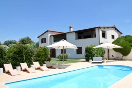 a pool with chairs and umbrellas in front of a house at Villa Linnazello - elegant pool villa with sea view near Rome/Tuscany in Tarquinia
