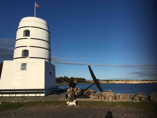 a man and a dog standing next to a lighthouse at Luksus hus i 1st række, all-incl top komfort med SPA og skov in Strøby
