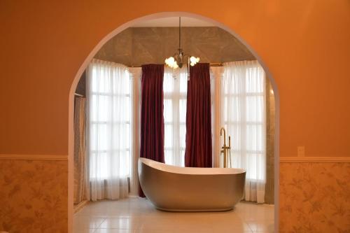 La salle de bains est pourvue d'une baignoire ovale devant les fenêtres. dans l'établissement Hotel Mansión Sant Serrant, à Marinilla