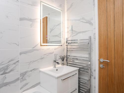 een witte badkamer met een wastafel en een spiegel bij The Cove in Holyhead
