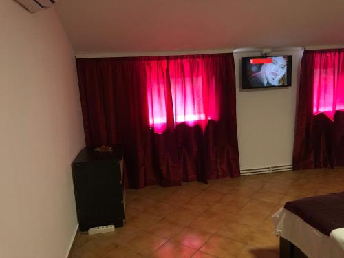 una camera da letto con tende rosse e TV in una stanza di Dark legend a Pucioasa