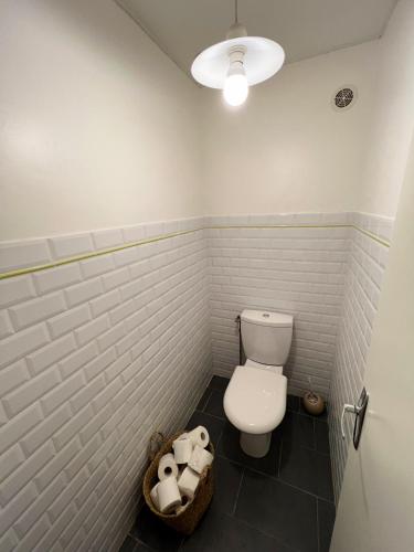 a bathroom with a toilet and a basket of toilet paper at L'Orée des Vignes - Maison Cosy avec Jardin Clos in Molosmes