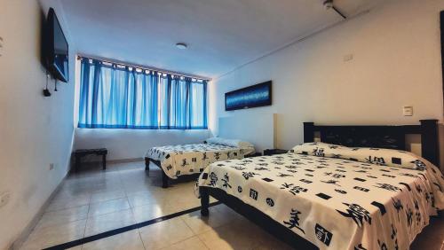 a bedroom with two beds and a window at Hotel Beijing Cartagena in Cartagena de Indias