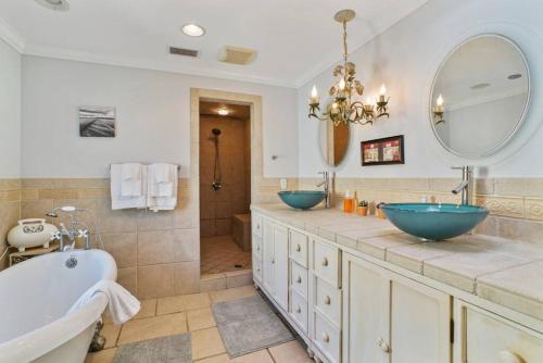 une salle de bain avec deux lavabos, une baignoire et un miroir dans l'établissement Sea Glass Cottage - An Oceanfront Experience, à Saint Augustine