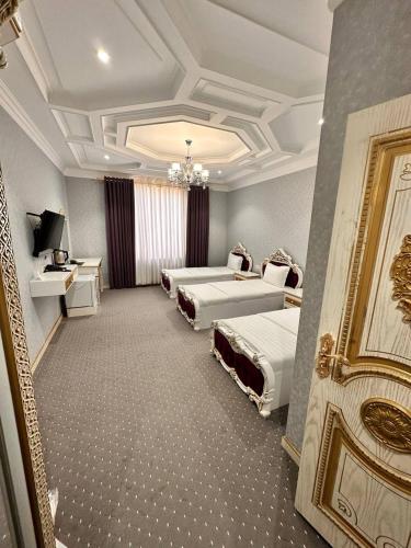 a hotel room with three beds and a chandelier at Suleyman hotel in Bukhara