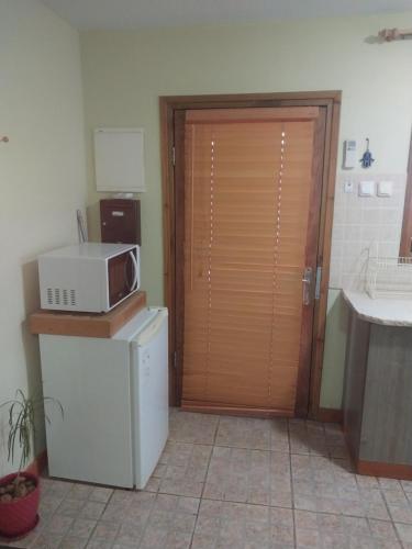 a kitchen with a door with a microwave on top of a refrigerator at בקתות קסם חרמון in Nimrod