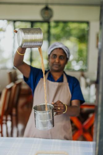 a man is holding a pot and holding a bucket at Misty Courtyard Resort in Chinnakanal