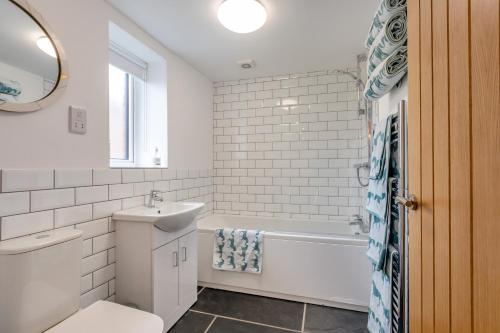 a bathroom with a sink and a tub and a toilet at The Hayloft in Tiverton