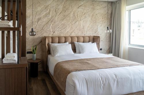 a bedroom with a large bed and a stone wall at Athens Design Suites in Athens