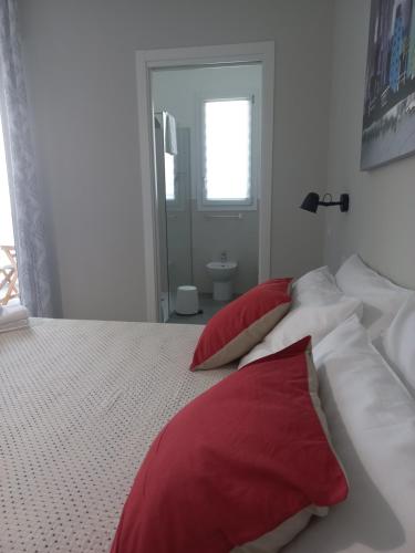a bedroom with a bed with red and white pillows at ViaRiva Rooms in Cagliari