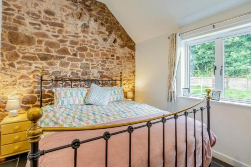 a bedroom with a bed and a stone wall at The Farm Office in Tiverton