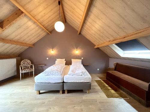 een slaapkamer met een bed en een bank op zolder bij Achter de Hegge in Riemst