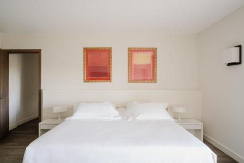 a bedroom with a white bed and two windows at Aethos Corsica in Oletta