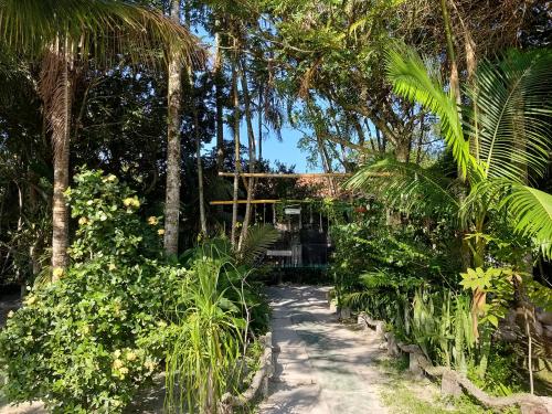 a path through the jungle with a house in the background at A Ilha Verde Hotel Pousada na Praia in Ilha do Mel