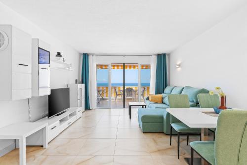 a living room with a couch and a table with chairs at Neptuno Ocean View, Beach line with Pool in Puerto de Santiago