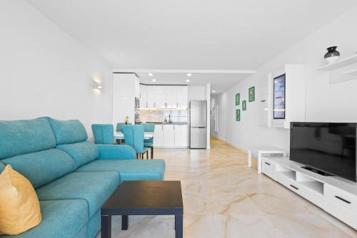 a living room with a blue couch and a kitchen at Neptuno Ocean View, Beach line with Pool in Puerto de Santiago