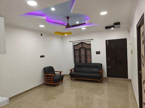 a living room with two chairs and a ceiling fan at Treva Pent House in Thirunallar