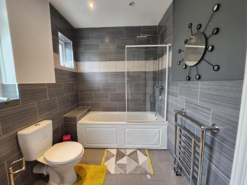 uma casa de banho com uma banheira, um WC e um chuveiro em Spacious Room with Garden in Croydon London em South Norwood